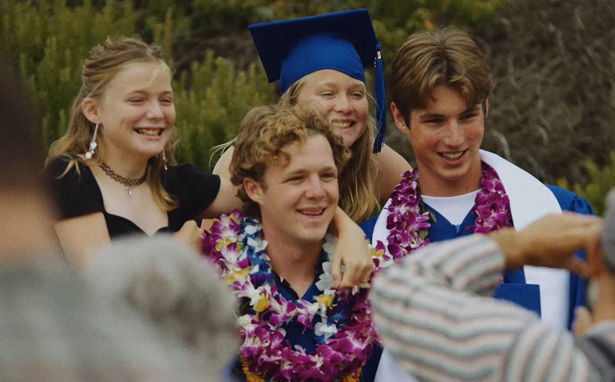 Students in graduation caps, gowns, and colorful flower leis