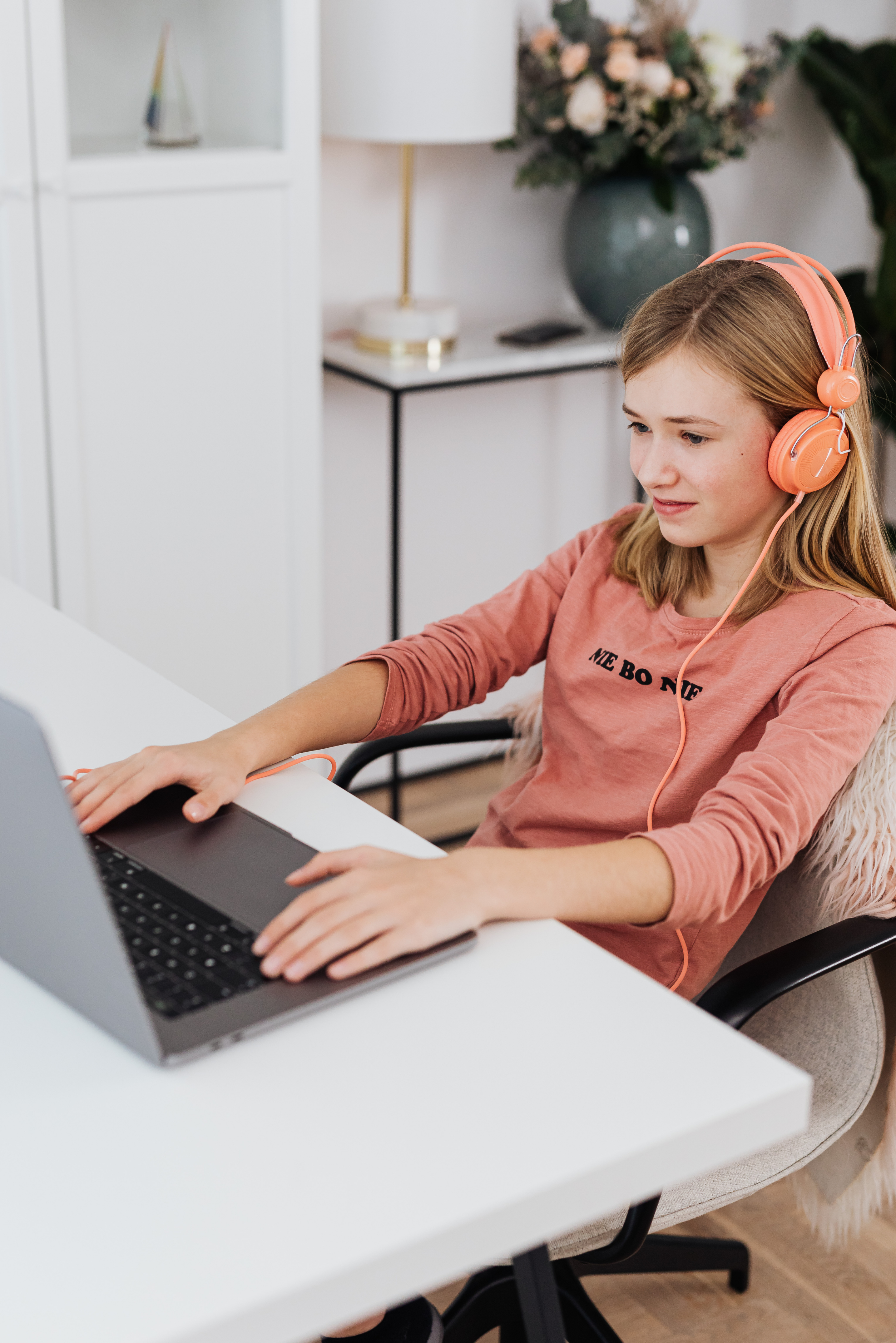 Student with pink headphones focused on her laptop